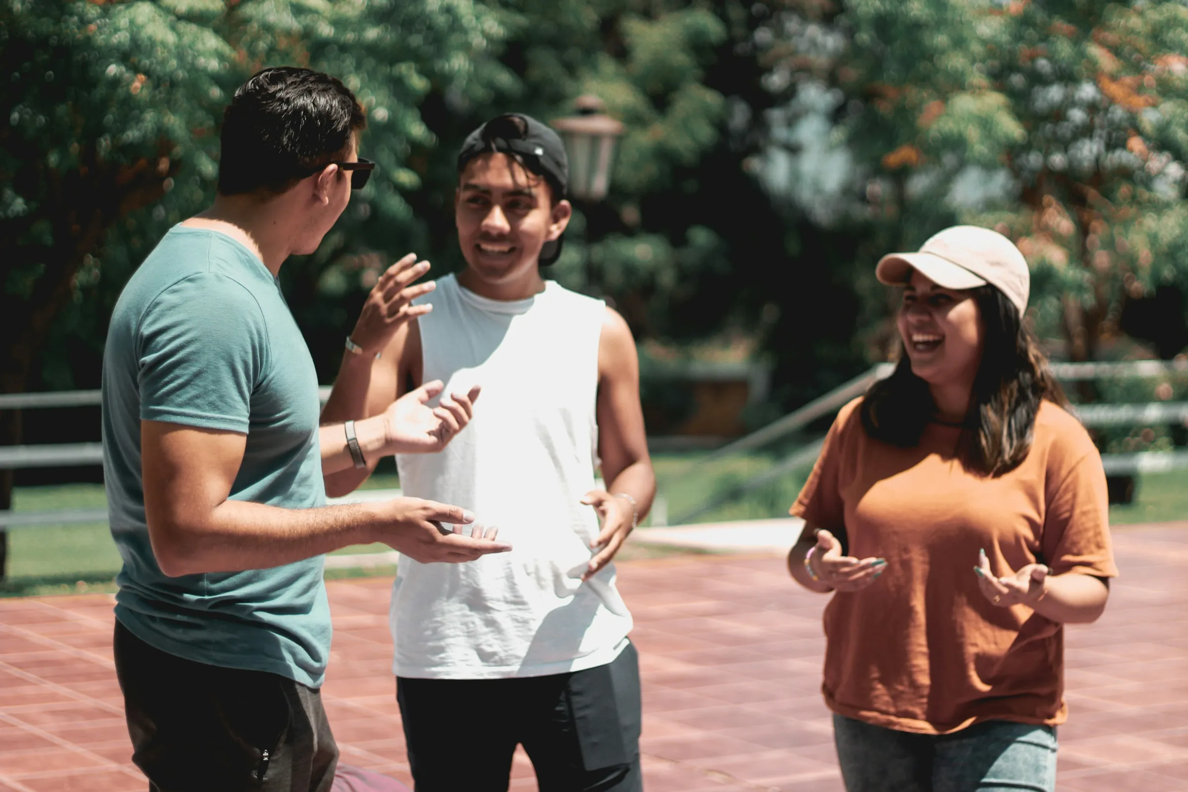 Three people talk and laugh outside on a brick plaza