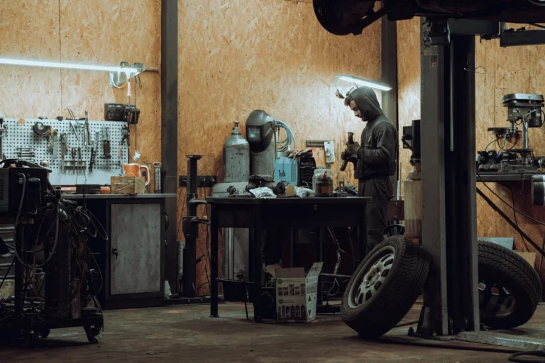 A mechanic works at a bench in a garage workshop