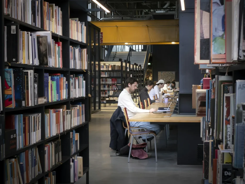 Students study at long wooden tables in a modern library