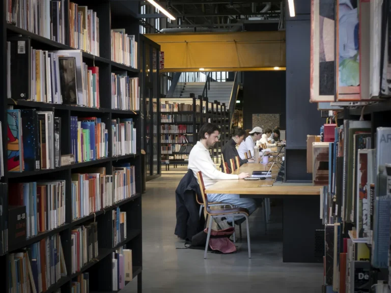 Students study at long wooden tables in a modern library